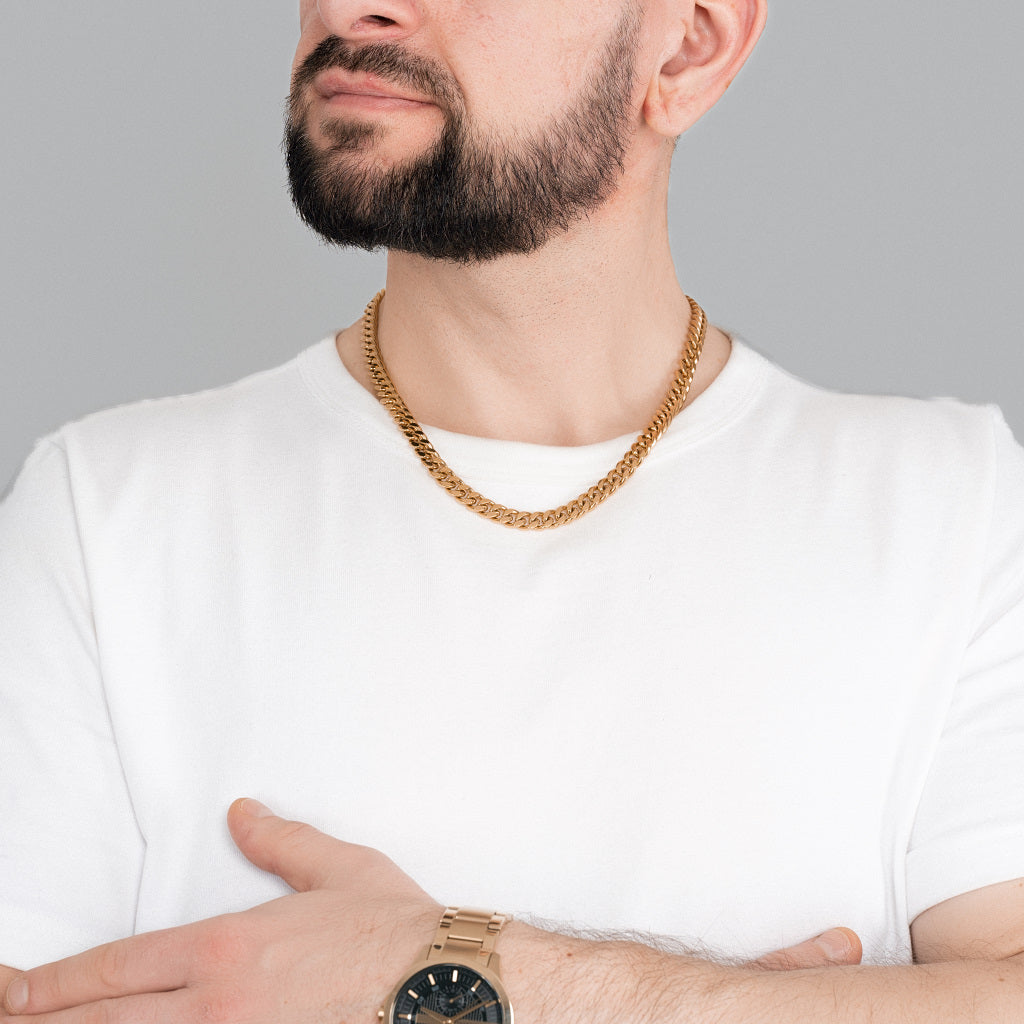 A bearded brutal man in white t-shirt wearing Gold Miami Cuban Chain 8 mm with gold watch to match the accessories to highlight the look.