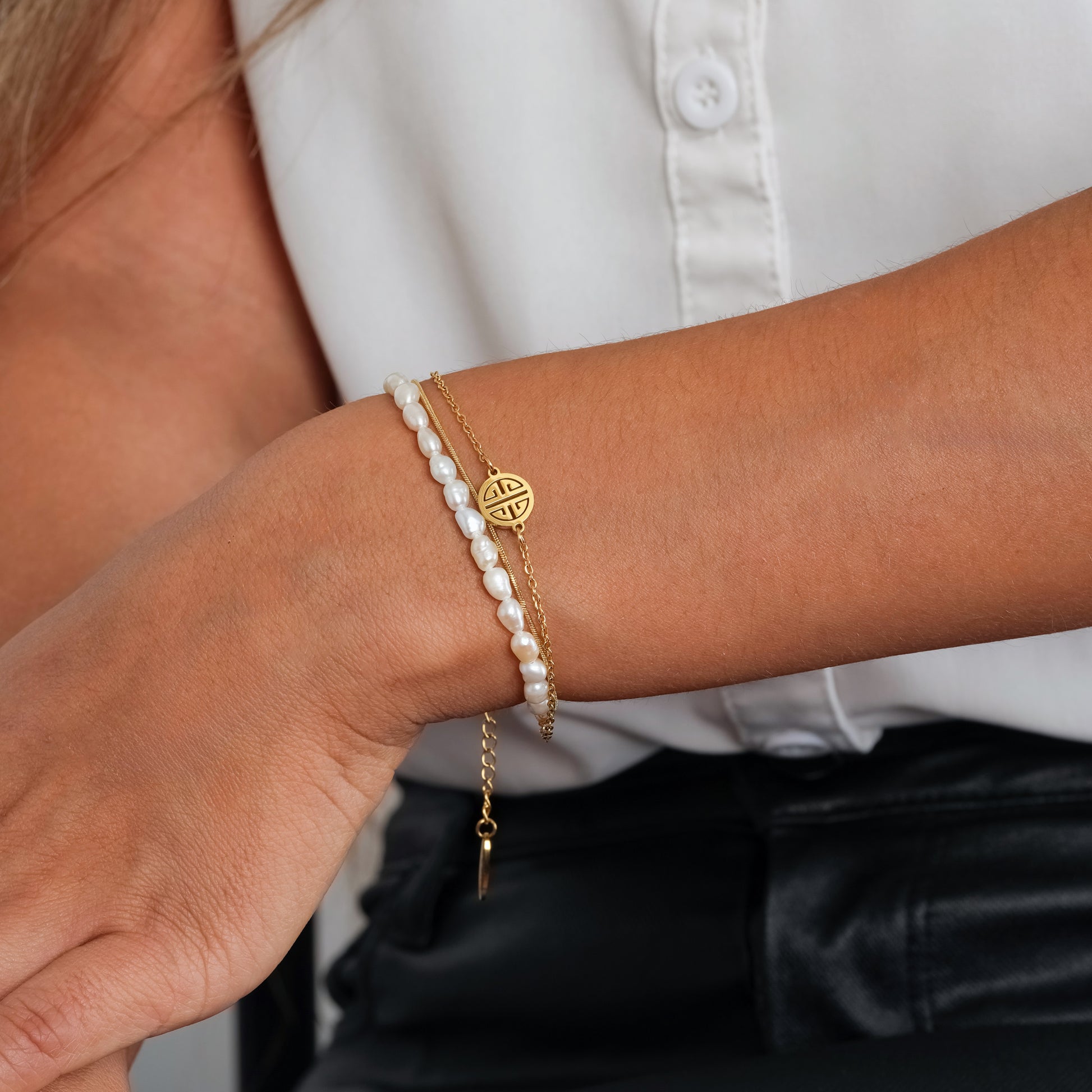 A model in a white sleeveless top wearing Lucky Pendant Pearl bracelet on her wrist. Close-up image of the bracelet.
