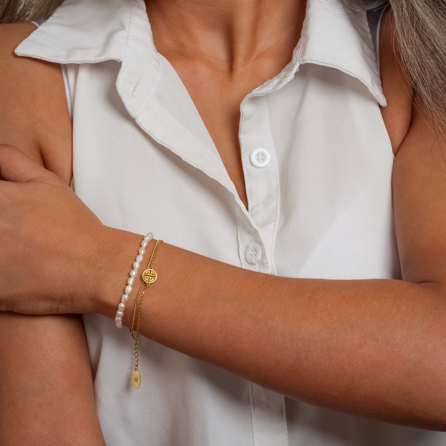 A model in a white sleeveless shirt wearing Lucky Pendant Pearl bracelet on her wrist.