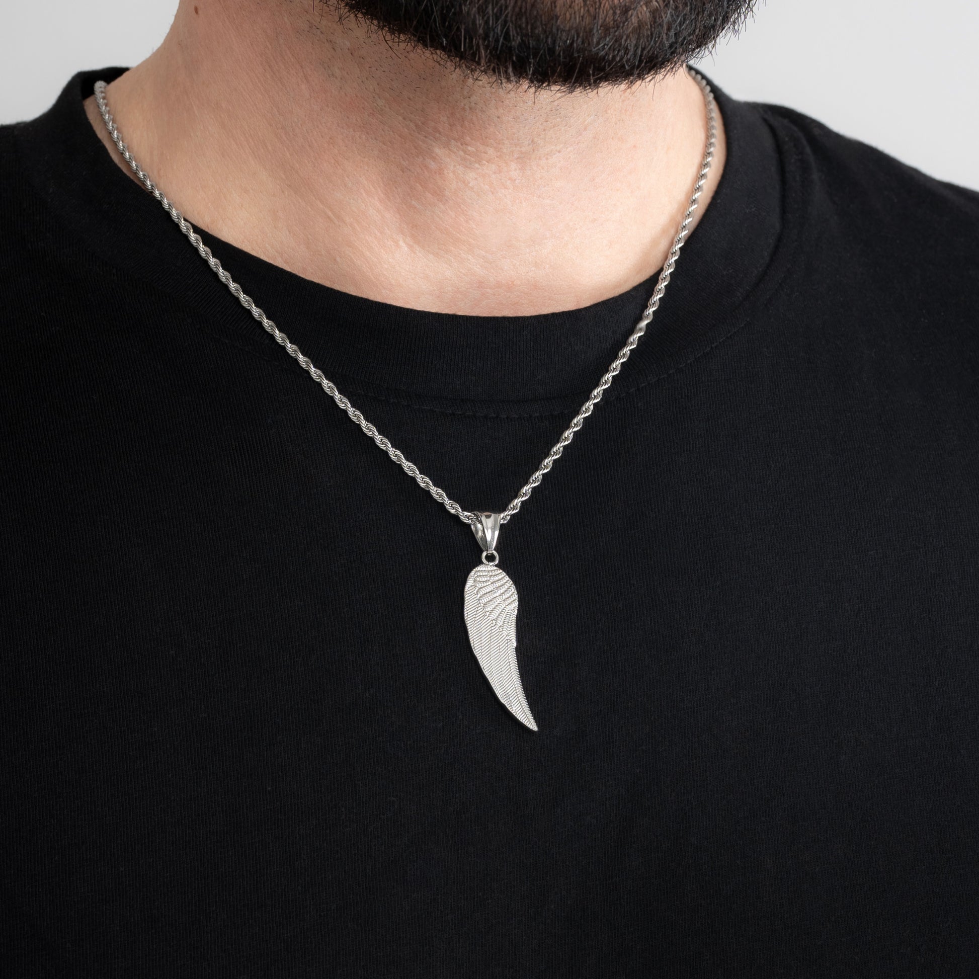 A male model in a black t-shirt wearing an Angel Wing Silver Pendant with a 3mm Silver Rope chain 22 inches. Close-up image of the non-tarnish, waterproof trending men's jewellery.