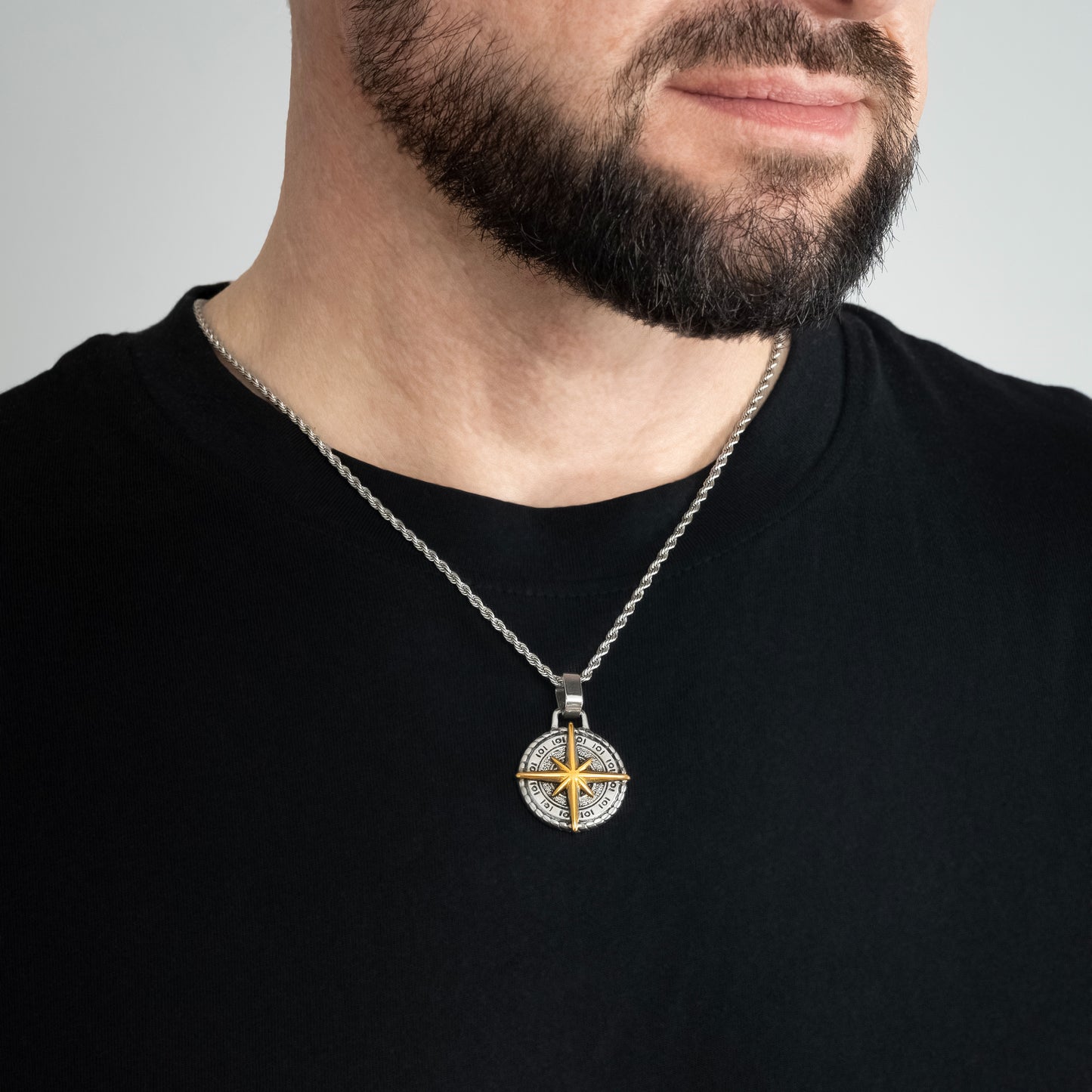 A male model in a black t-shirt wearing a Compass North Star Pendant with a Silver Rope chain 22 inches. Close-up image of the trending non-tarnish necklace.