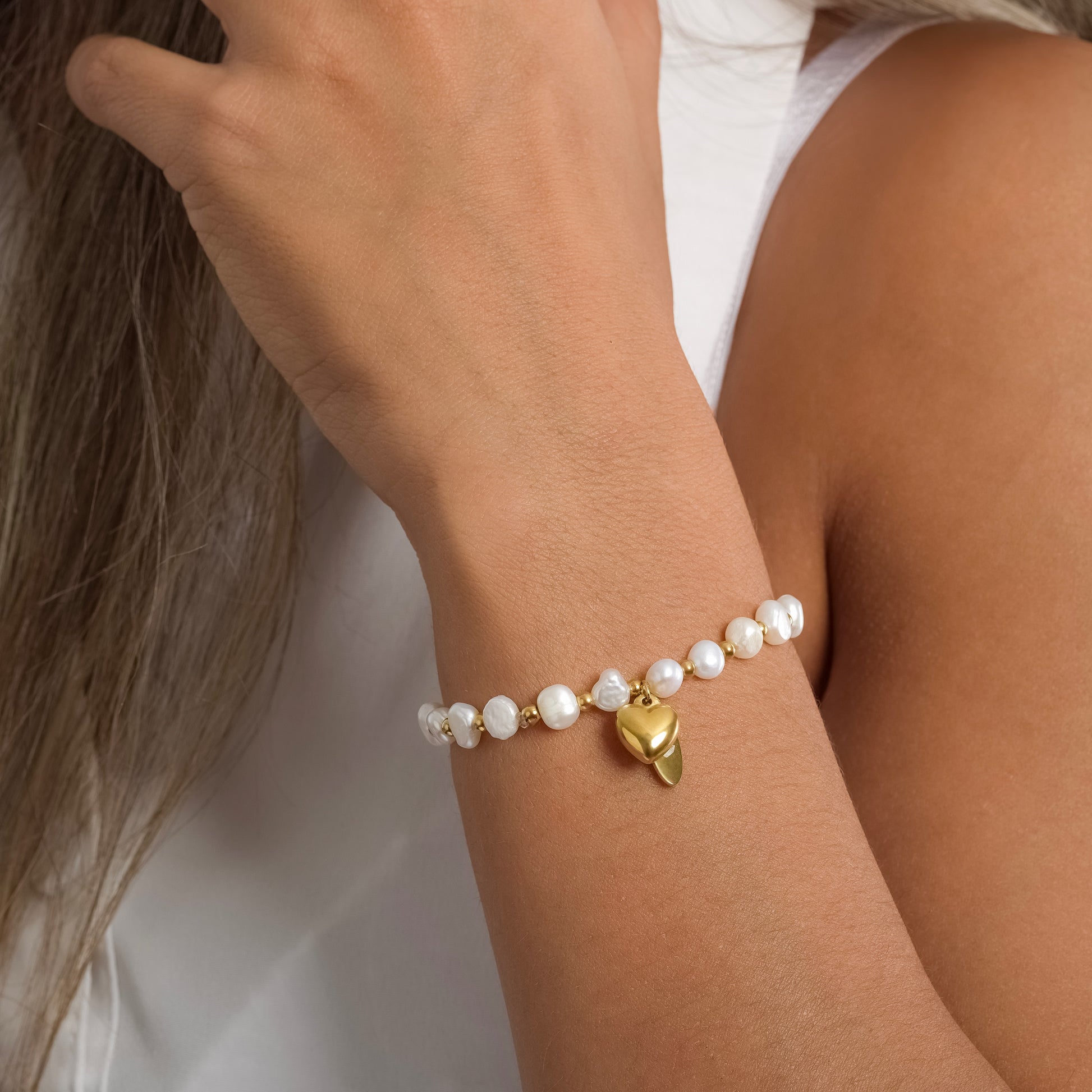 A model in a white sleeveless top wearing Heart Beaded Pearl bracelet on her wrist. Close-up image of the bracelet.