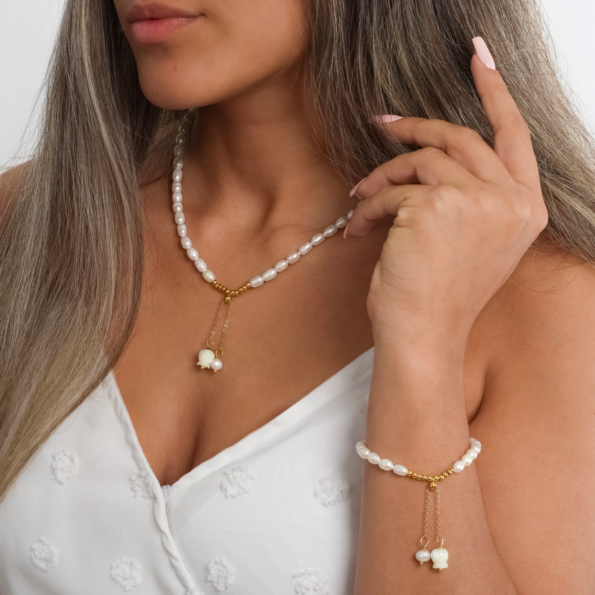 A model in a white dress wearing Lily of the Valley Pearl Necklace paired with Lily of the Valley Pearl Bracelet on her wrist