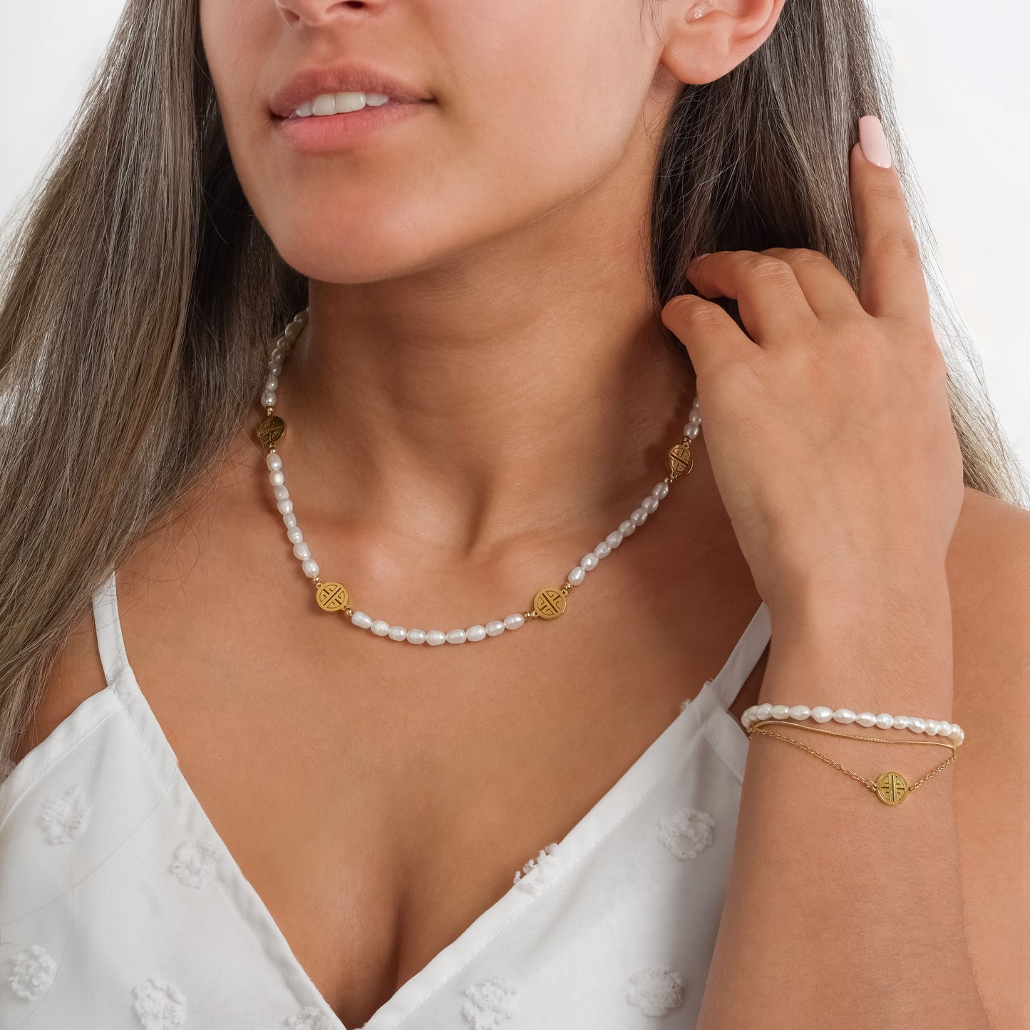 A model in a white dress wearing Lucky Pendant Pearl Necklace on her neck paired with Lucky Pendant Pearl Bracelet on her wrist