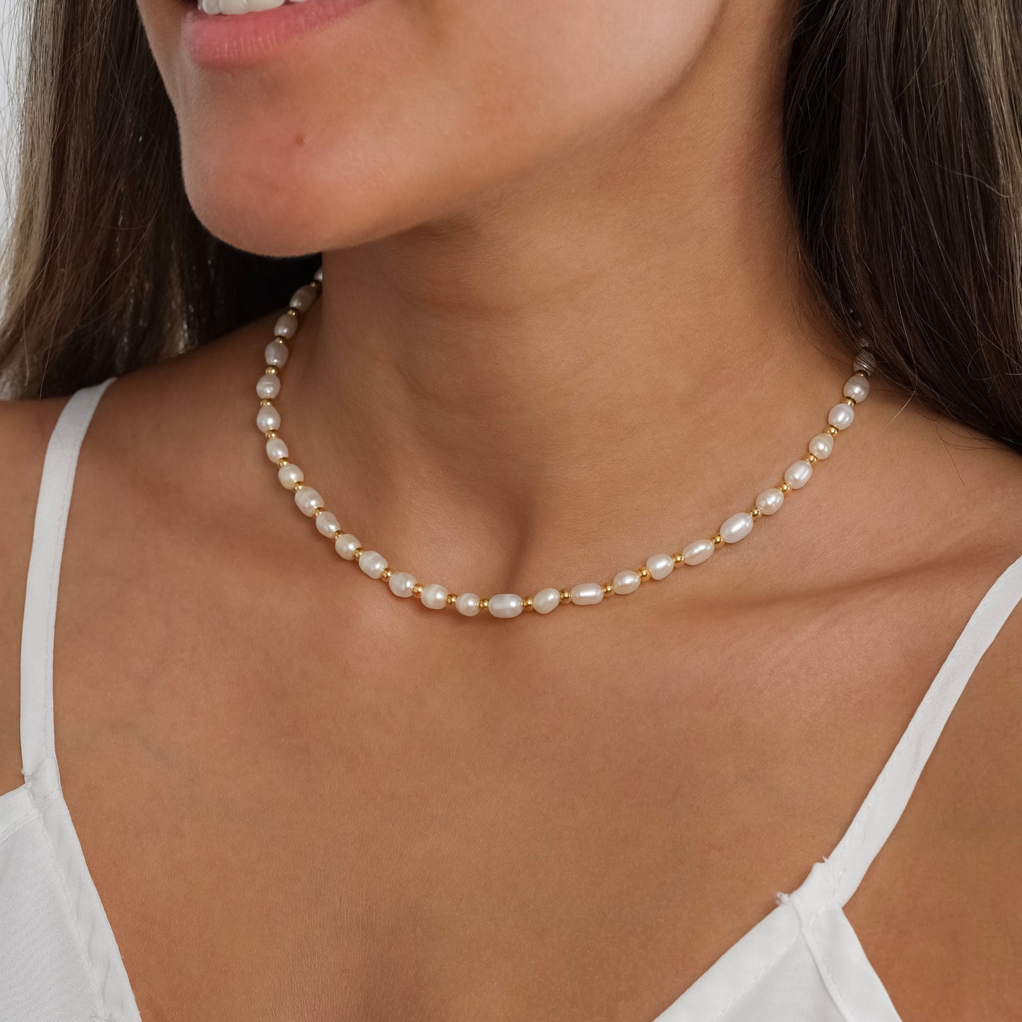 A model in a white dress wearing Gold Bead Pearl Necklace