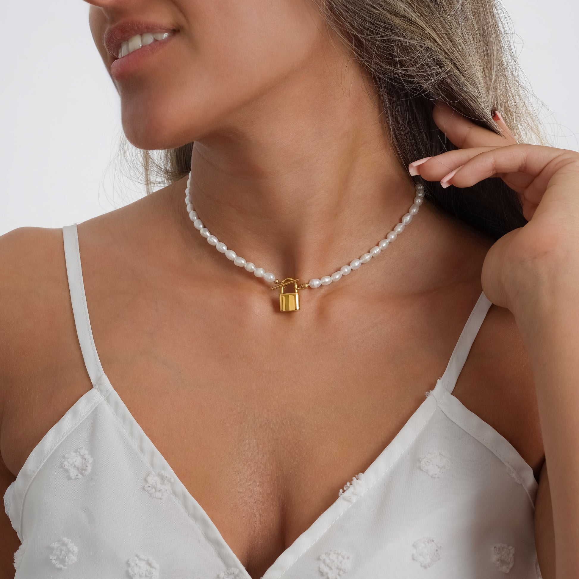 A model in a white dress wearing Padlock Pearl Necklace