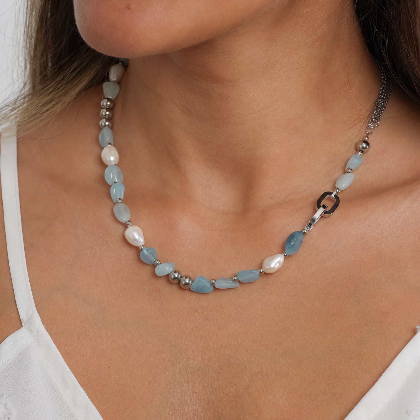 A model in a white dress wearing Aquamarine Stone & Pearl Beaded Necklace. Close-up image of the necklace.