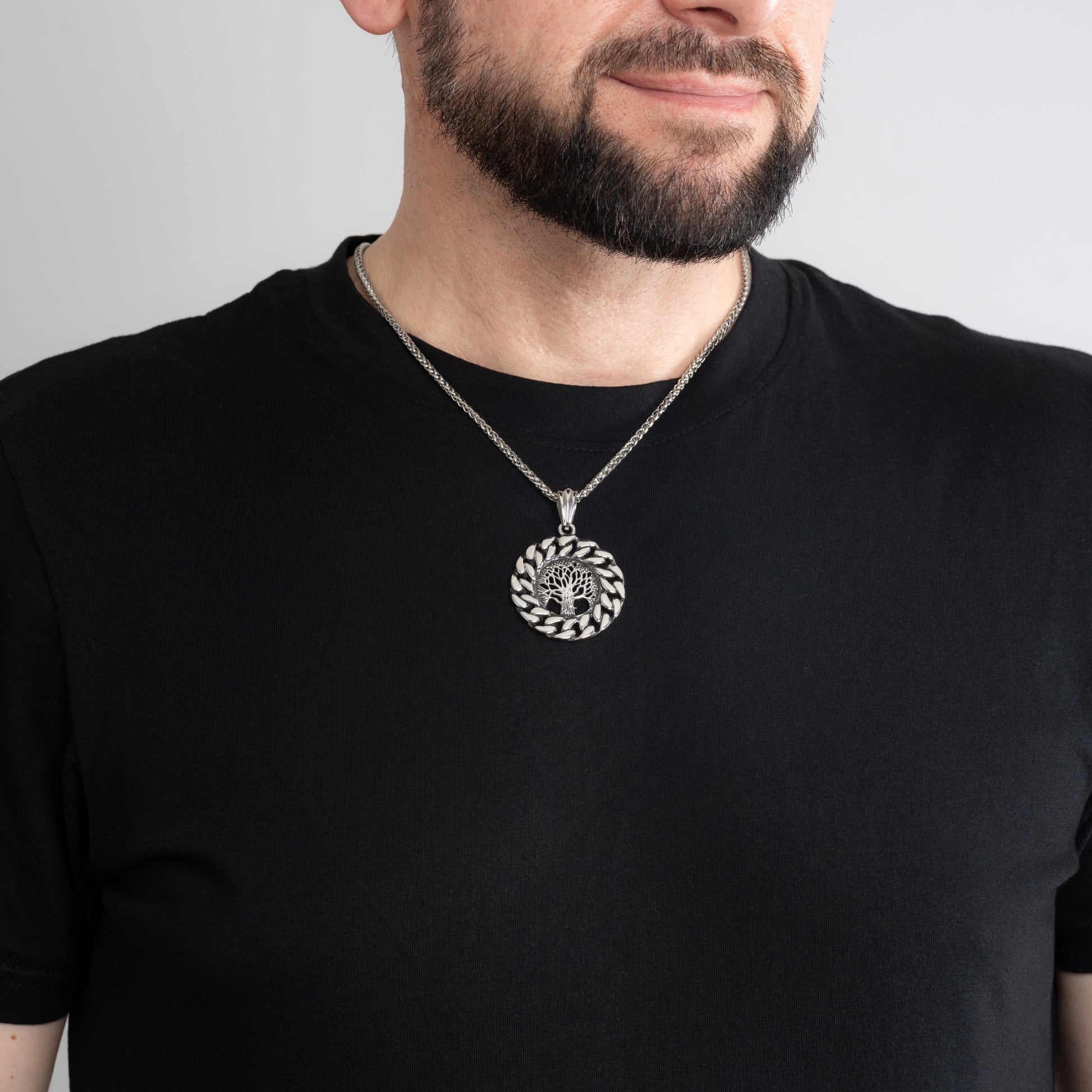 A male model in a black t-shirt wearing a Vintage Tree of Life Silver Pendant with a 3mm Silver Spiga chain 20 inches.