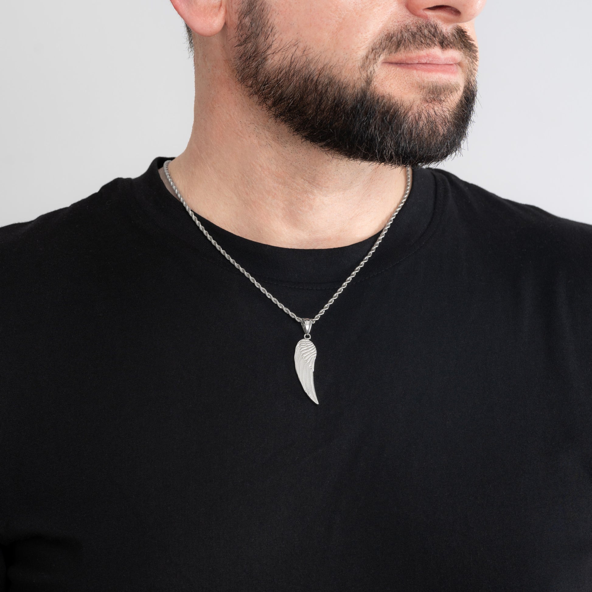 A male model in a black t-shirt wearing an Angel Wing Silver Pendant with a 3mm Silver Rope chain 22 inches.