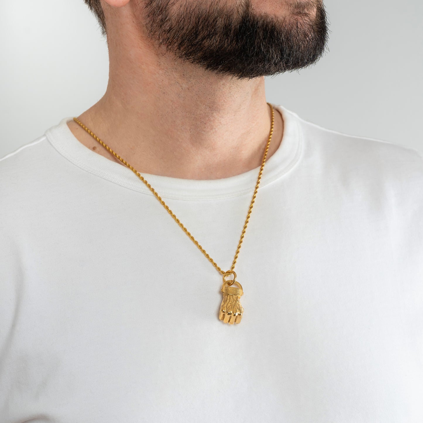 A male model in a white t-shirt wearing a Fist Gold Pendant with a Gold Rope chain 22 inches.