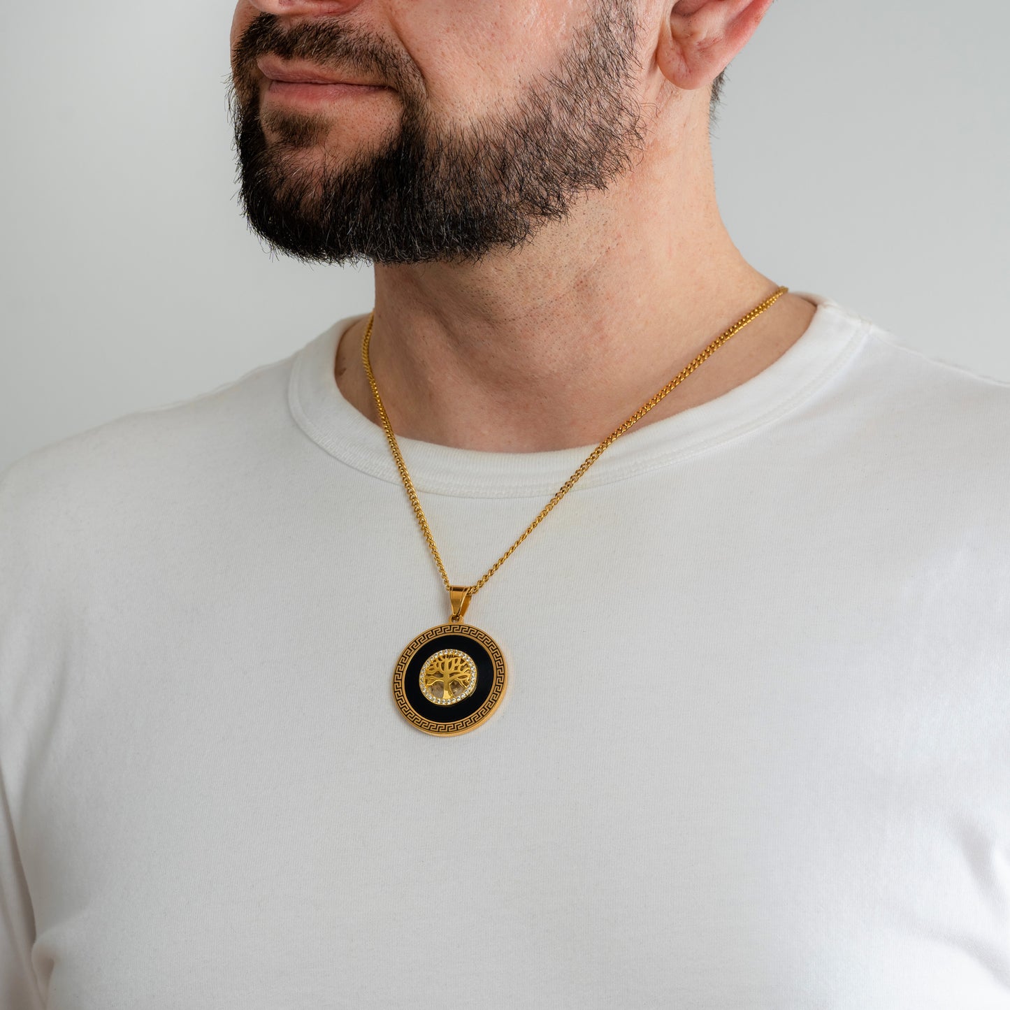 A male model in a white t-shirt wearing an Iced Tree of Life Gold Pendant with a 3mm Micro Cuban chain 22 inches.