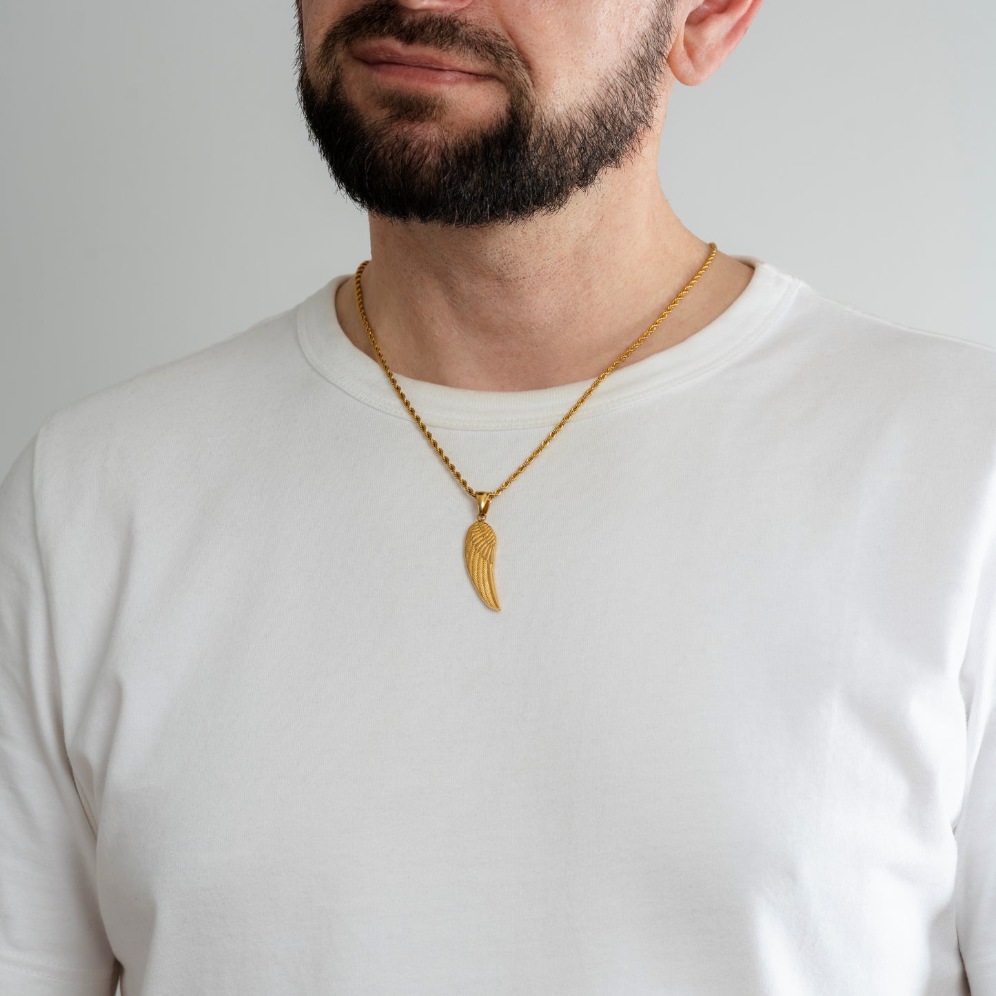 A male model in a white t-shirt wearing an Angel Wing Gold Pendant with a 3mm Gold Rope chain 22 inches.