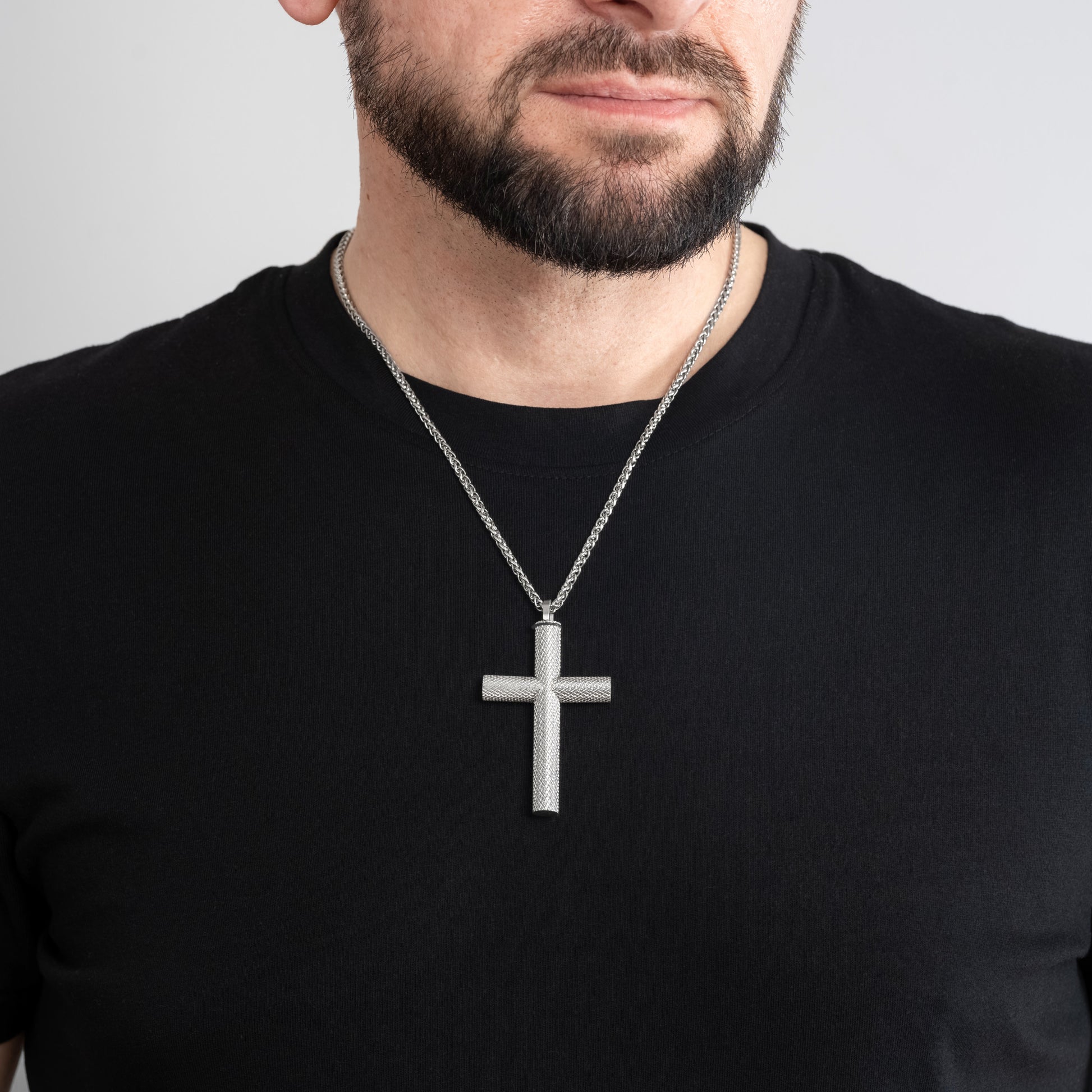 A male model in a black t-shirt wearing a Bison Cross Silver Self-fill Pendant with a 3mm Silver Spiga chain 22 inches.