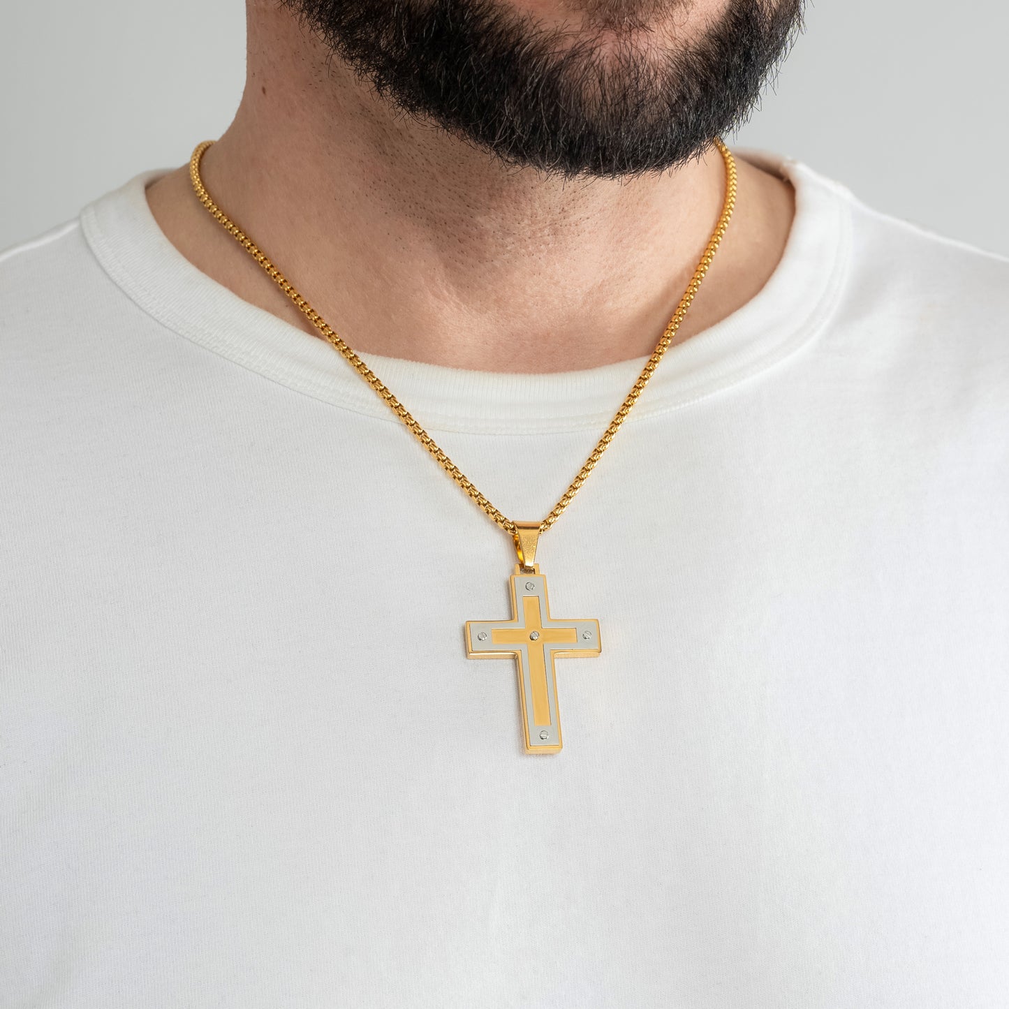 A male model in a white t-shirt wearing an Armour Gold Pendant with a 3mm Gold Round Box link chain 22 inches. Close-up image of the non-tarnish trending religious men's necklace.