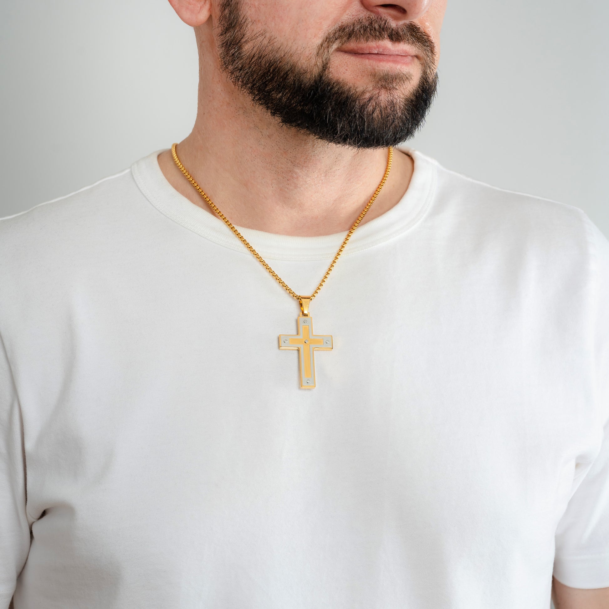 A male model in a white t-shirt wearing an Armour Cross Gold Pendant with a 3mm Gold Round box chain 22 inches.