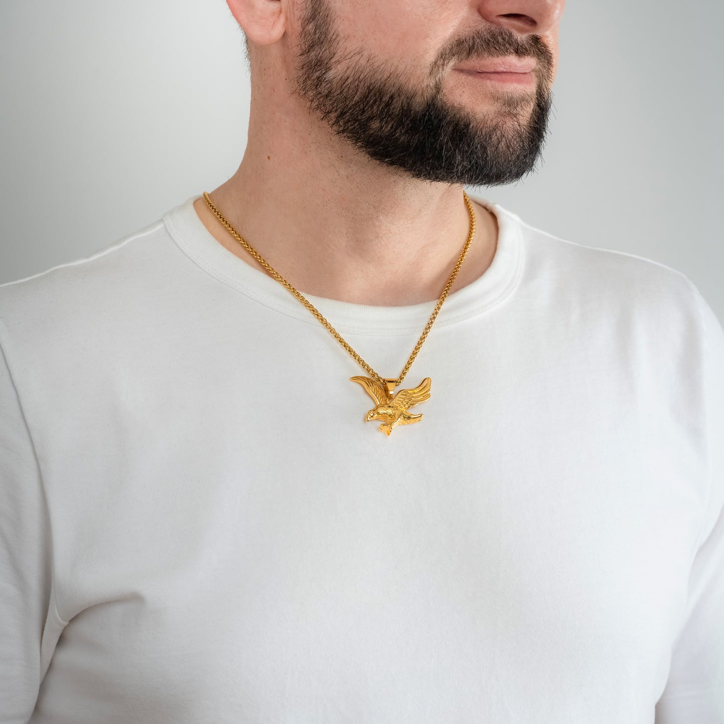 A male model in a white t-shirt wearing a Eagle Gold Pendant with a 3mm Spiga (Wheat) Gold chain 22 inches.