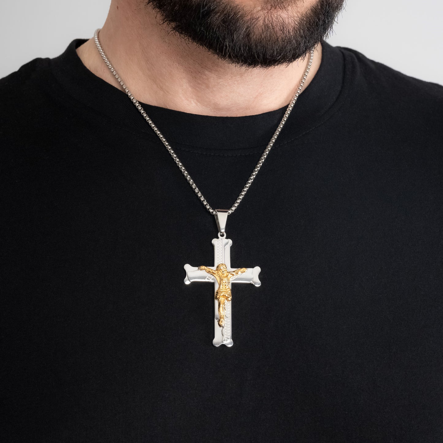 A male model in a black t-shirt wearing a Bliss Crucifix Cross Pendant with a 3mm Round Box Link Silver chain 22 inches.