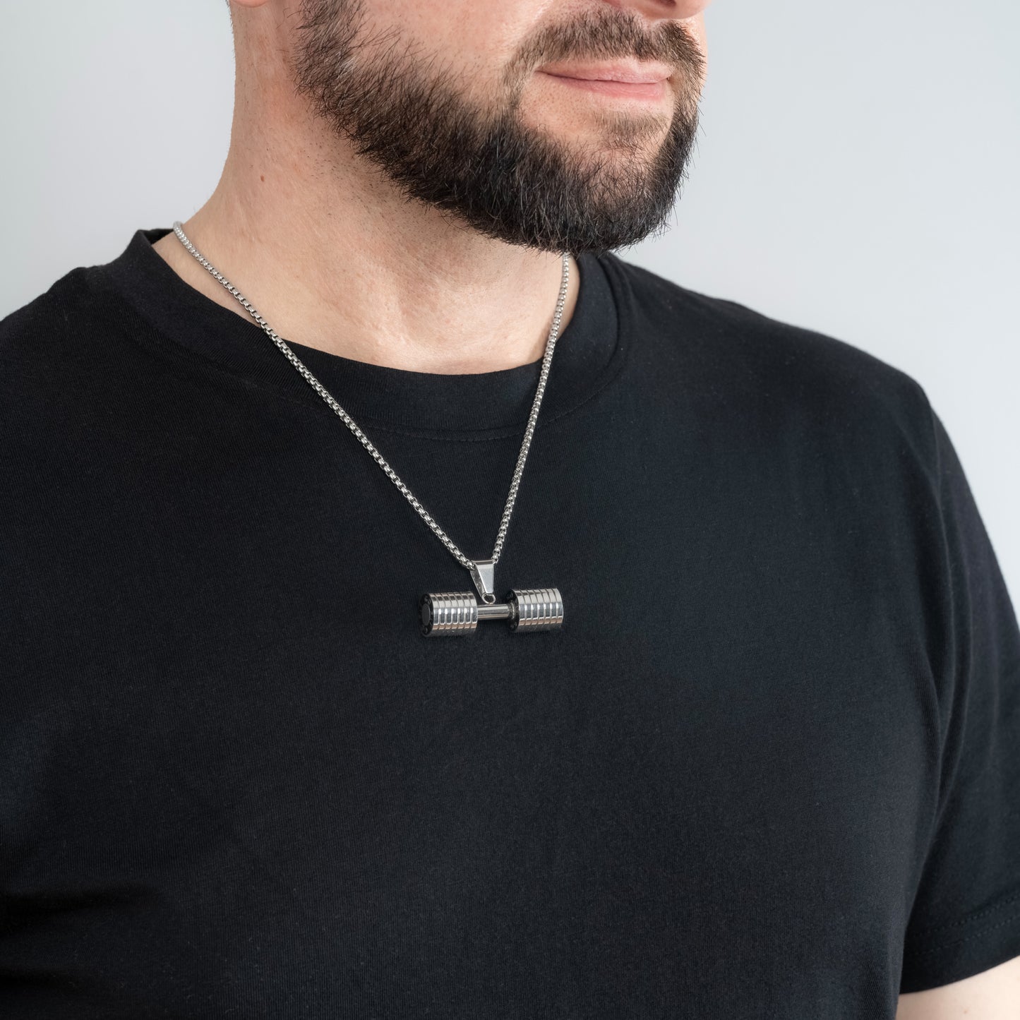 A male model in a black t-shirt wearing a Dumbbell Fitness Silver Pendant with a 3mm Round Box link Silver chain 22 inches.
