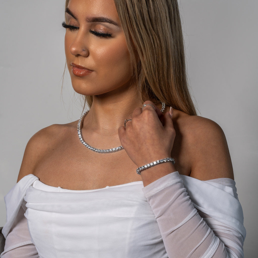 Stunning female model in white dress wearing Cubic Zirconia 5mm Silver Tennis Necklace paired with matching 5mm Silver Tennis bracelet set