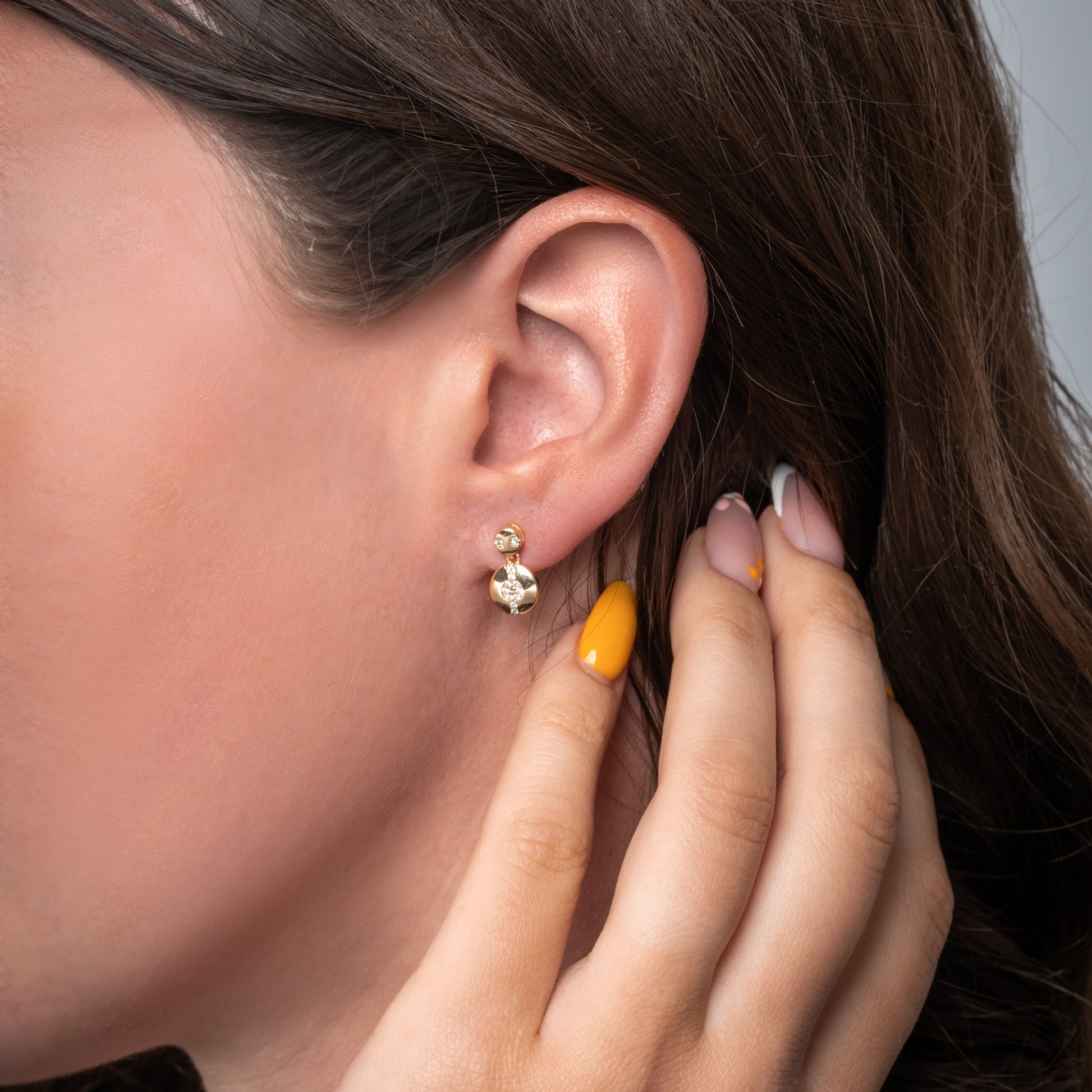 A model showing Hypnotic Solar Gold Earrings in her ear