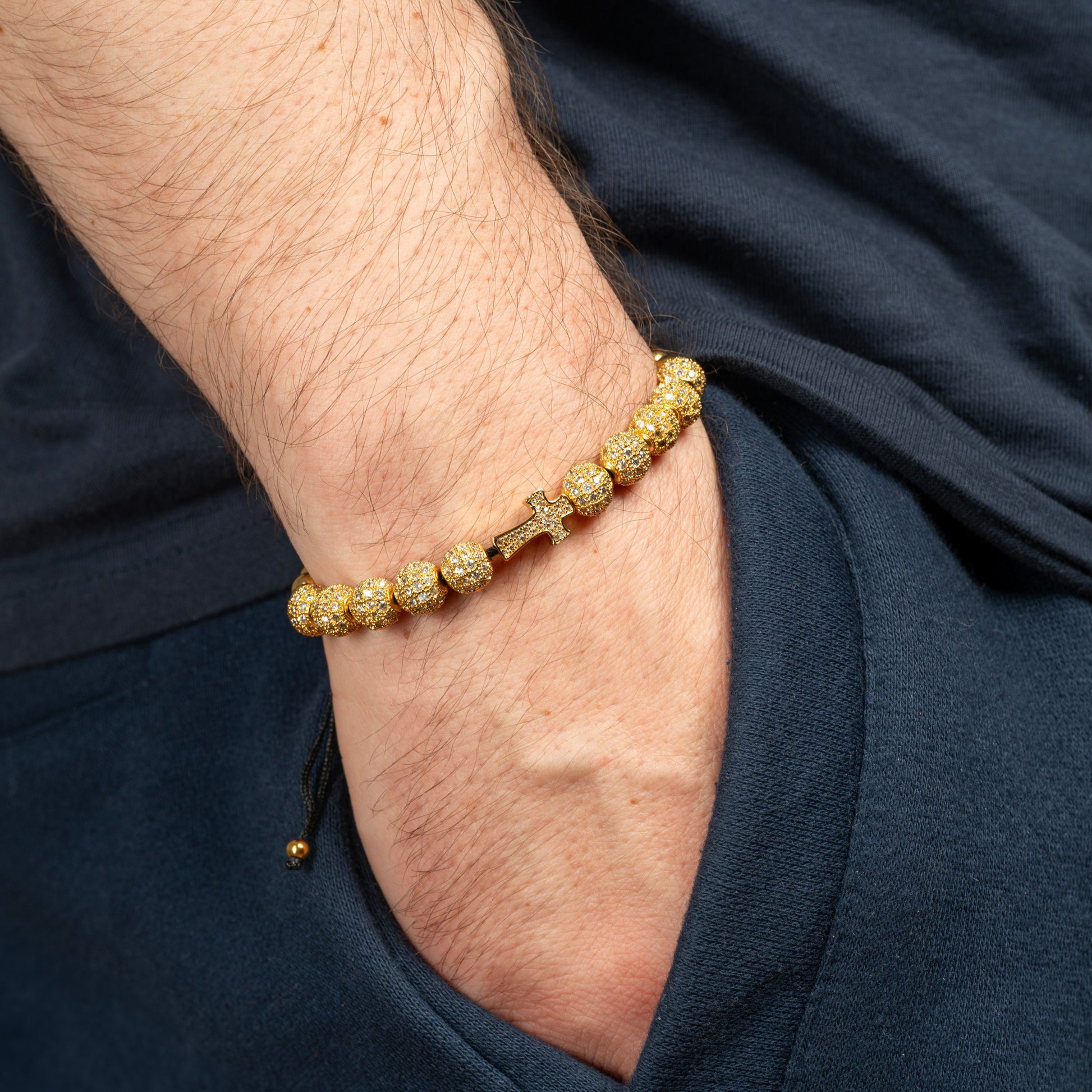 Model wearing Royal Cross Bracelet in Gold on his wrist.