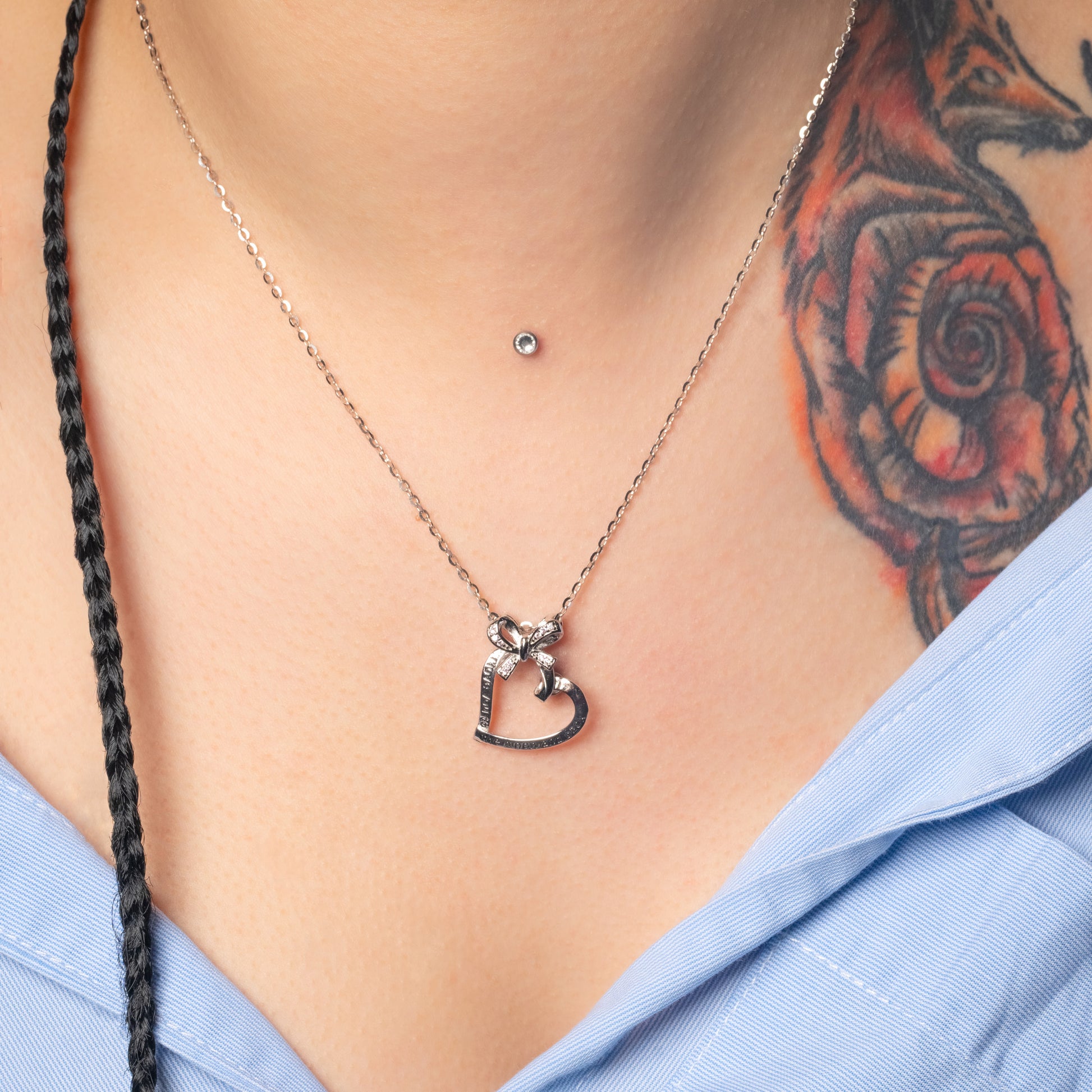 Model wearing Bow Heart Silver Pendant with Flat Cable necklace. Zoomed-in view.
