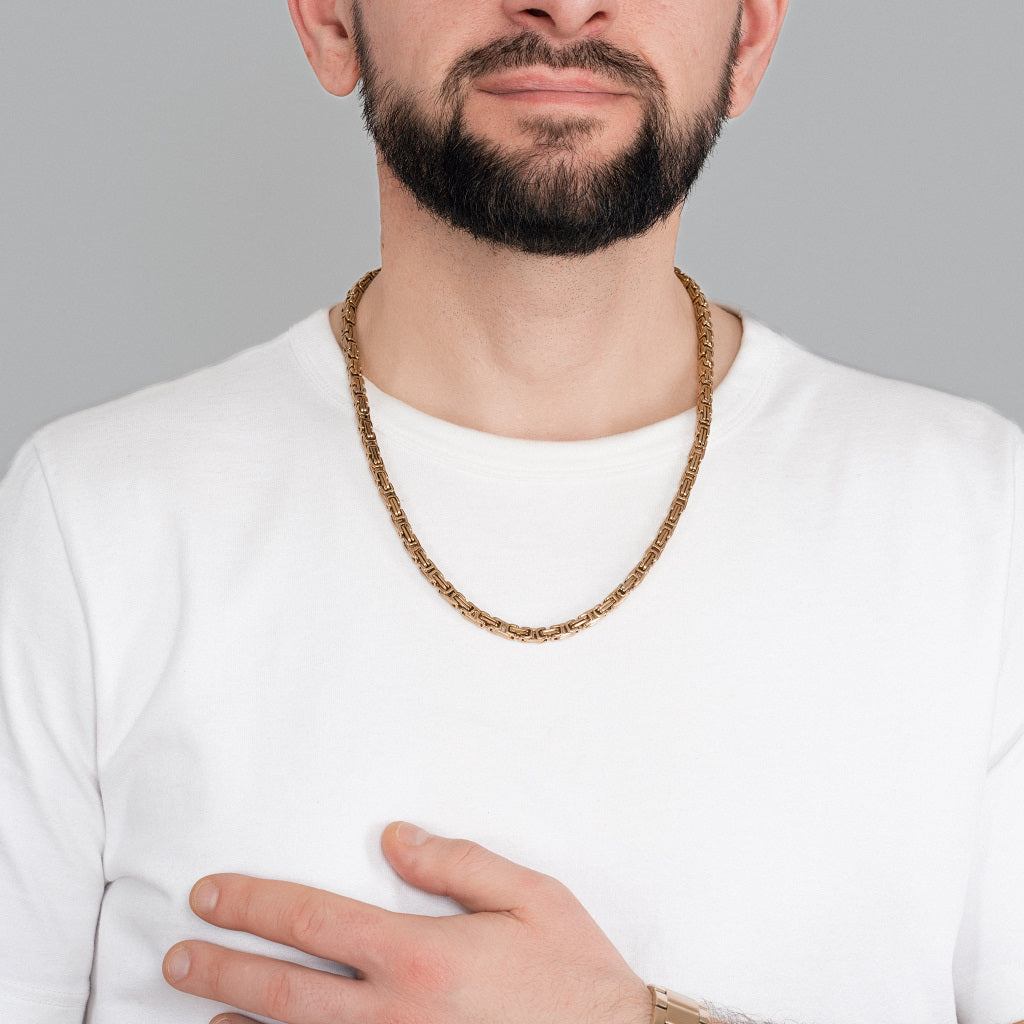 A bearded man in white t-shirt wearing Gold Byzantine Box link Chain 5mm, 24 inches with a gold watch to perfectly match the accessories