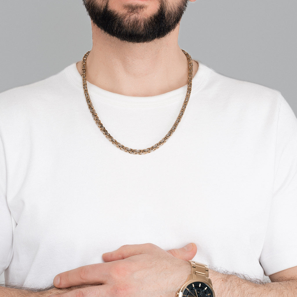 A bearded man in white t-shirt wearing 2 tone Gold Silver Byzantine Box link Chain 5mm, 24 inches with a gold watch to nicely match the accessories