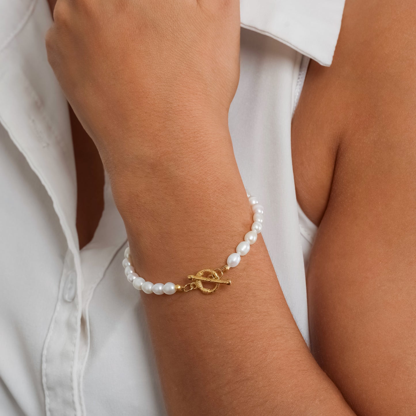 A model in a white sleeveless top wearing Toggle Clasp Pearl bracelet on her wrist.