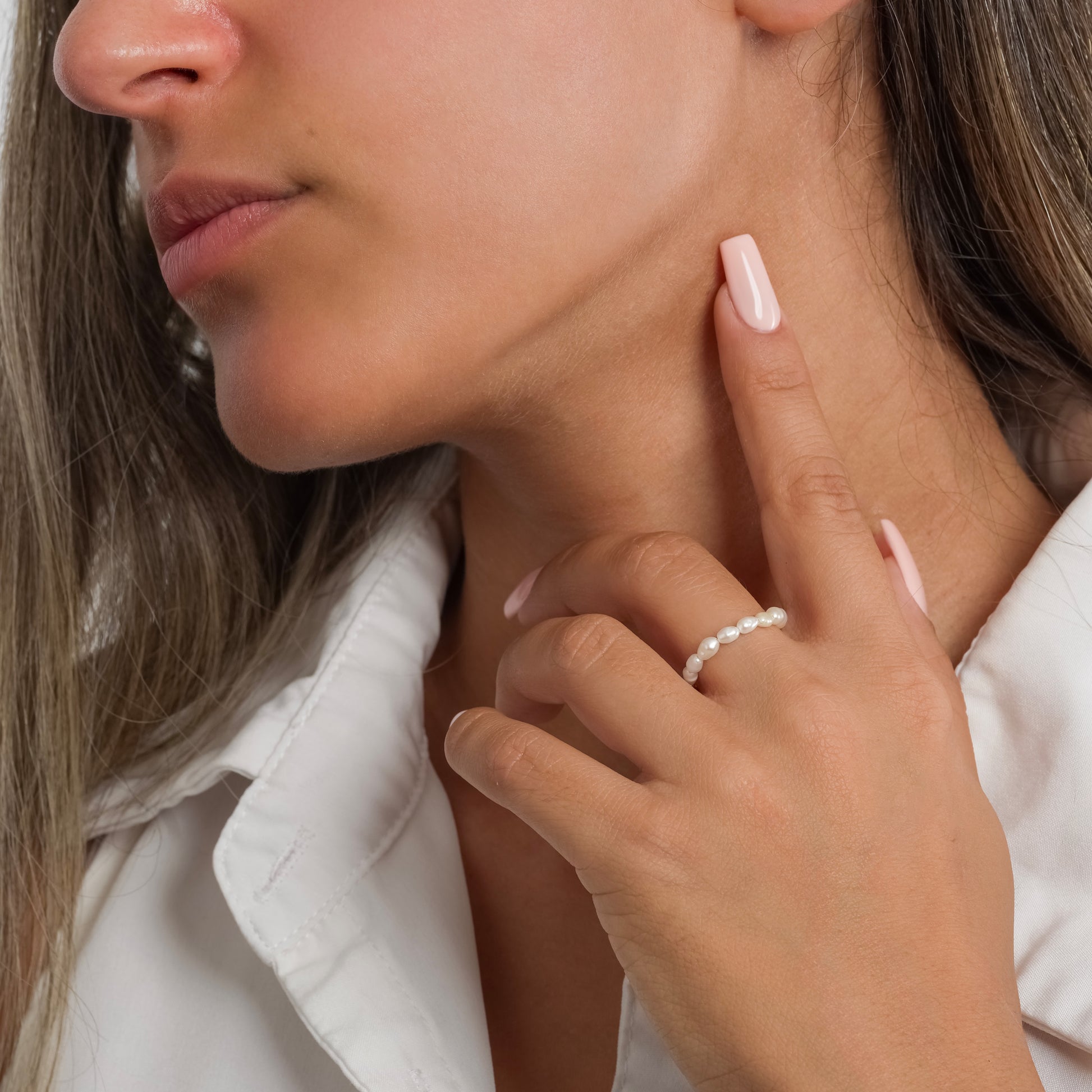 A model in a white sleeveless top wearing Freshwater Pearl ring on her finger.