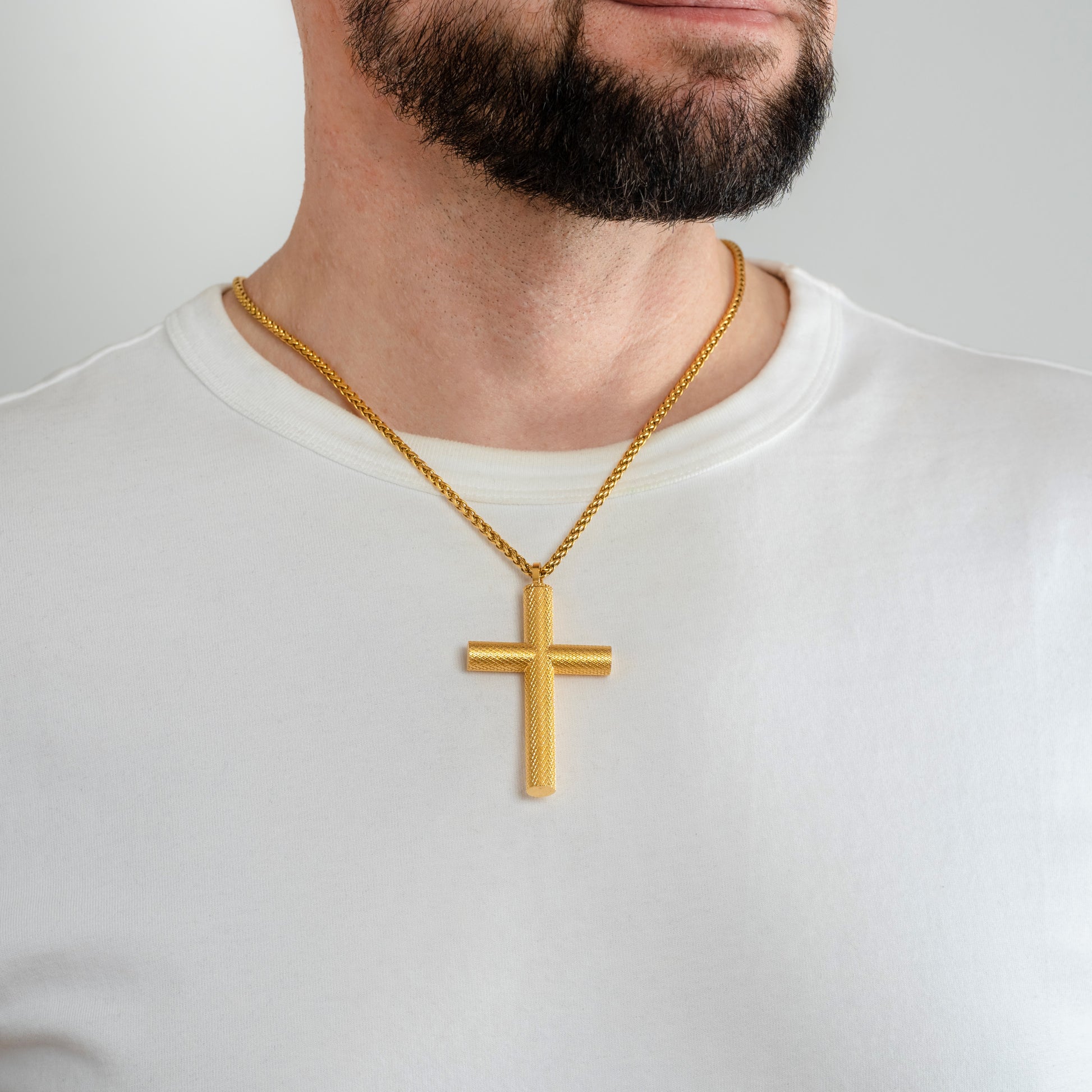 A male model in a white t-shirt wearing a Bison Cross Gold Self-fill Pendant with a 3mm Gold Spiga chain 22 inches.