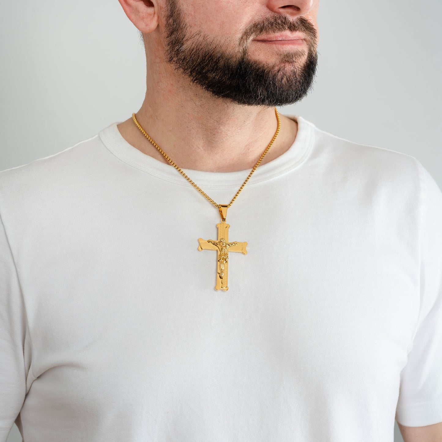 A male model in a white t-shirt wearing a Bliss Crucifix Cross Gold Pendant with a 3mm Gold Rope chain 22 inches.