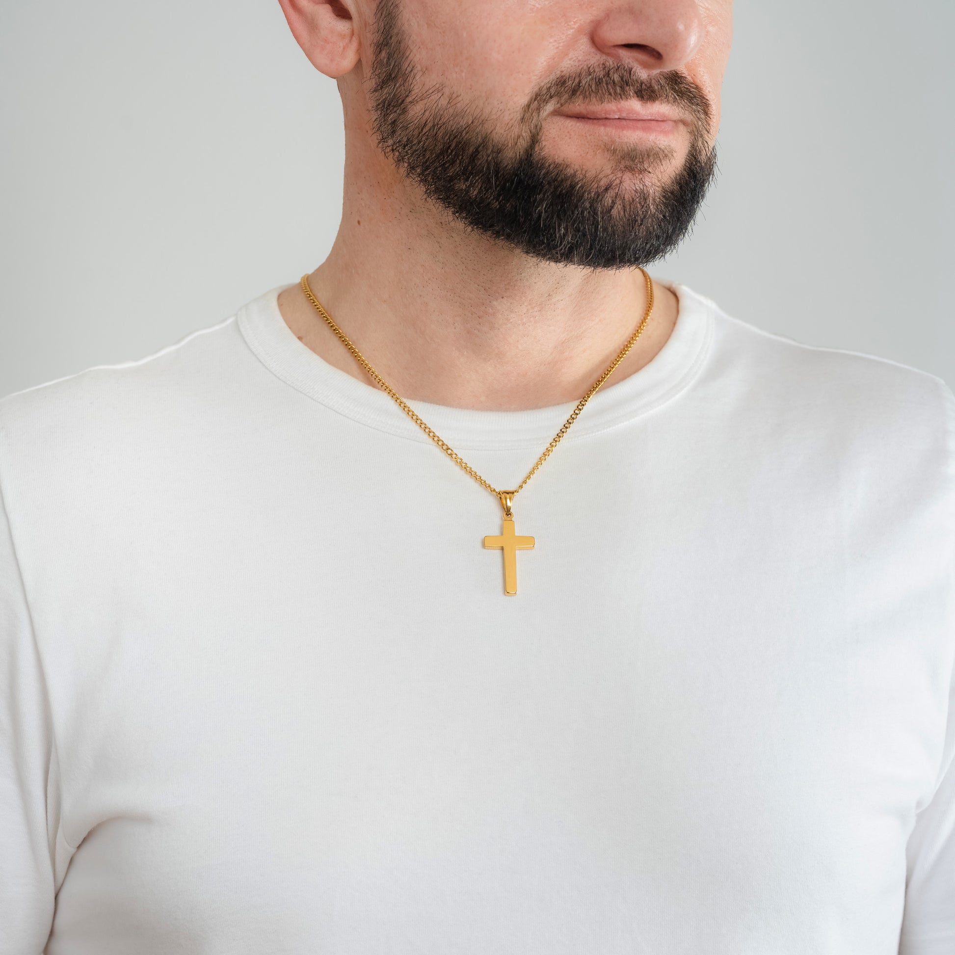 A male model in a white t-shirt wearing a Classic Cross Gold Pendant with a 3mm Micro Cuban Gold chain 22 inches.
