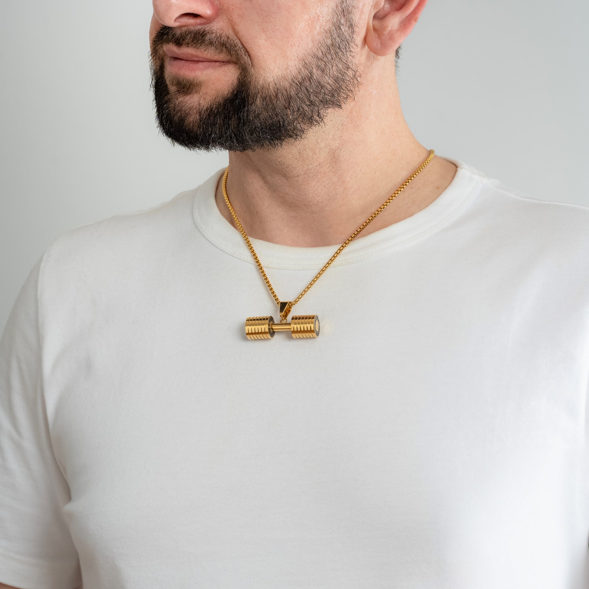 A male model in a white t-shirt wearing a Dumbbell Fitness Gold Pendant with a 3mm Round Box link Gold chain 22 inches.