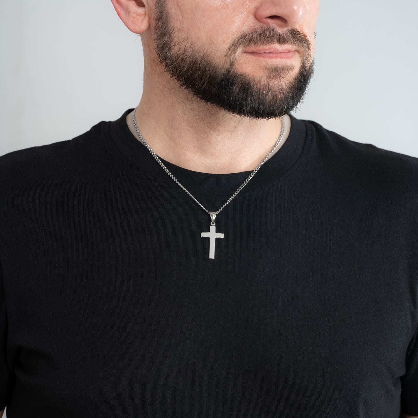 A male model in a black t-shirt wearing a Classic Cross Silver Pendant with a 3mm Silver Micro Cuban chain 22 inches.