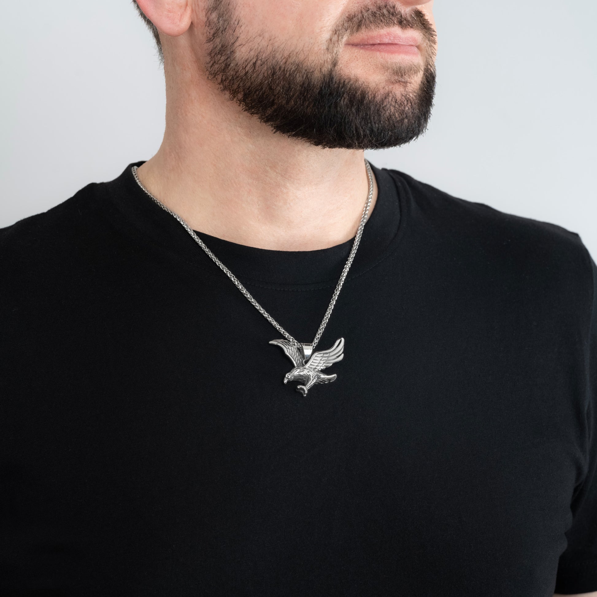 A male model in a black t-shirt wearing a Eagle Silver Pendant with a 3mm Spiga (Wheat) Silver chain 22 inches