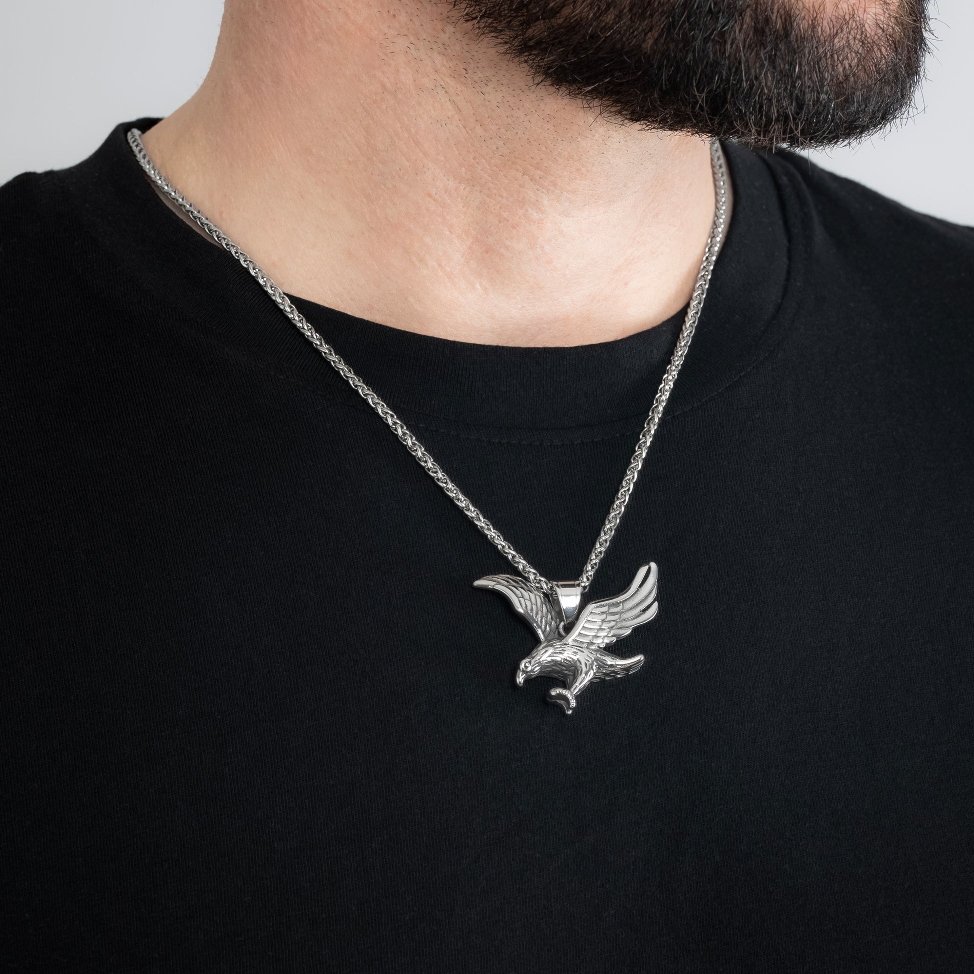 A male model in a black t-shirt wearing a Eagle Silver Pendant with a 3mm Spiga (Wheat) Silver chain 22 inches. Close-up image of the tarnish-free, sweatproof and waterproof powerful men's necklace.