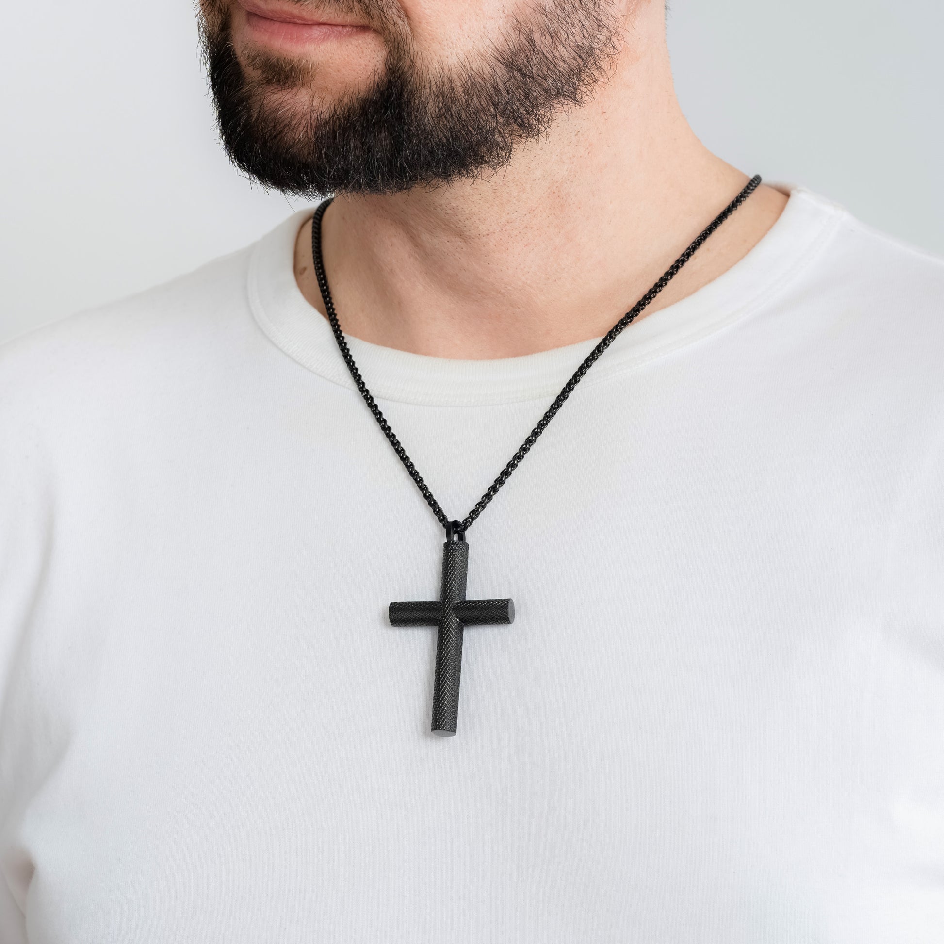A male model in a white t-shirt wearing a Bison Cross Black Self-fill Pendant with a 3mm Black Spiga chain 24 inches.