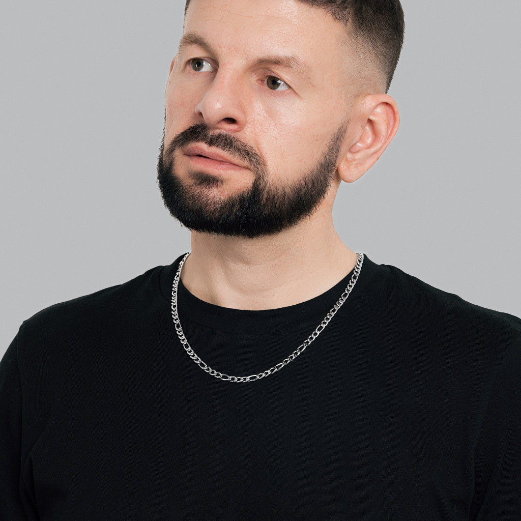 A bearded male model in black t-shirt wearing Silver Figaro Link Chain 5 mm, statement, lifetime, stainless steel, hypoallergenic men's jewellery