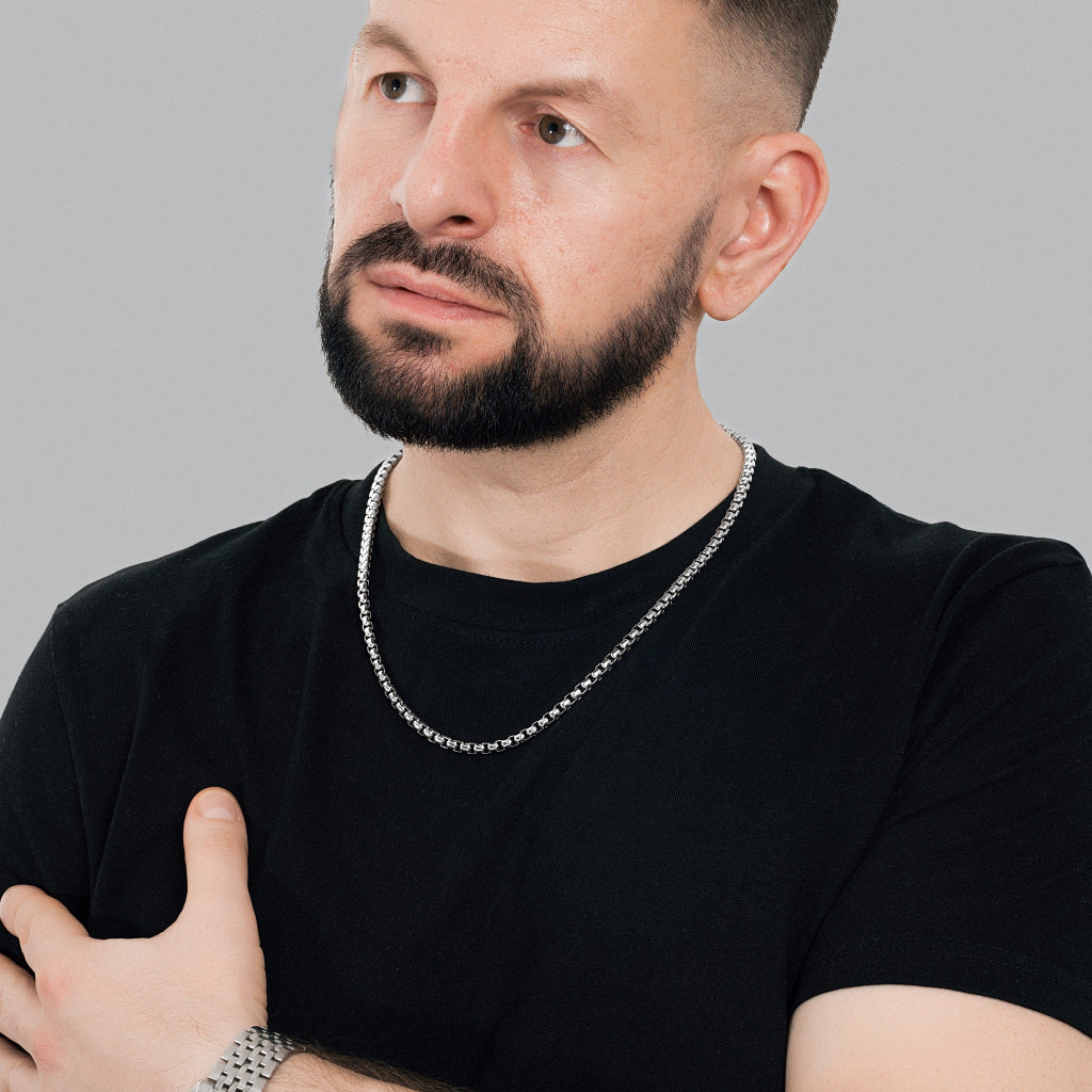 A bearded male model in black t-shirt wearing Silver Round Box Link Chain 5 mm with silver watch to match the accessories.